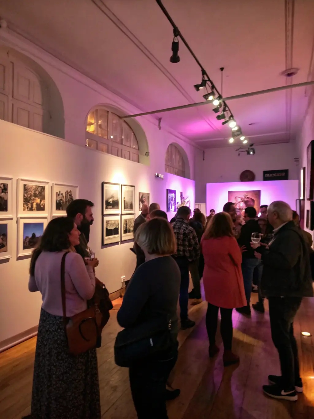 A photograph capturing the opening night of an artists' book exhibition, featuring diverse artworks and attendees engaging in conversation and appreciation.